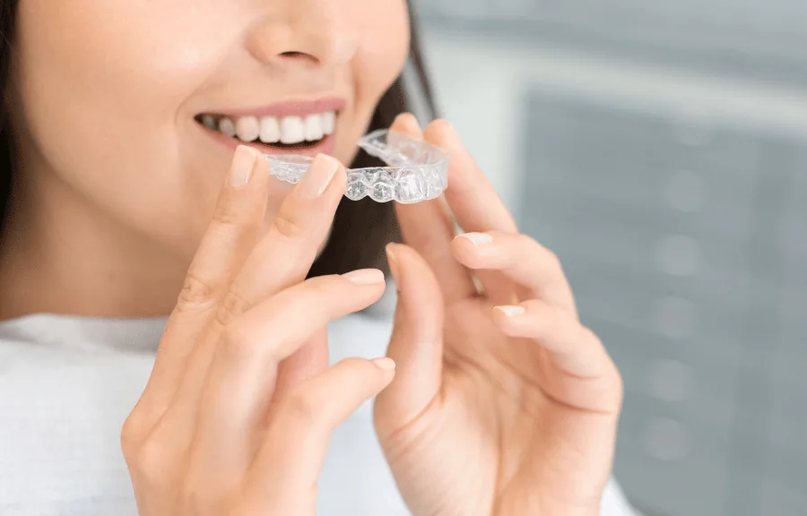 Frau setzt Invisalign-Schienen ein für eine Zahnkorrektur bei einem Kieferorthopäden in Luxemburg.
